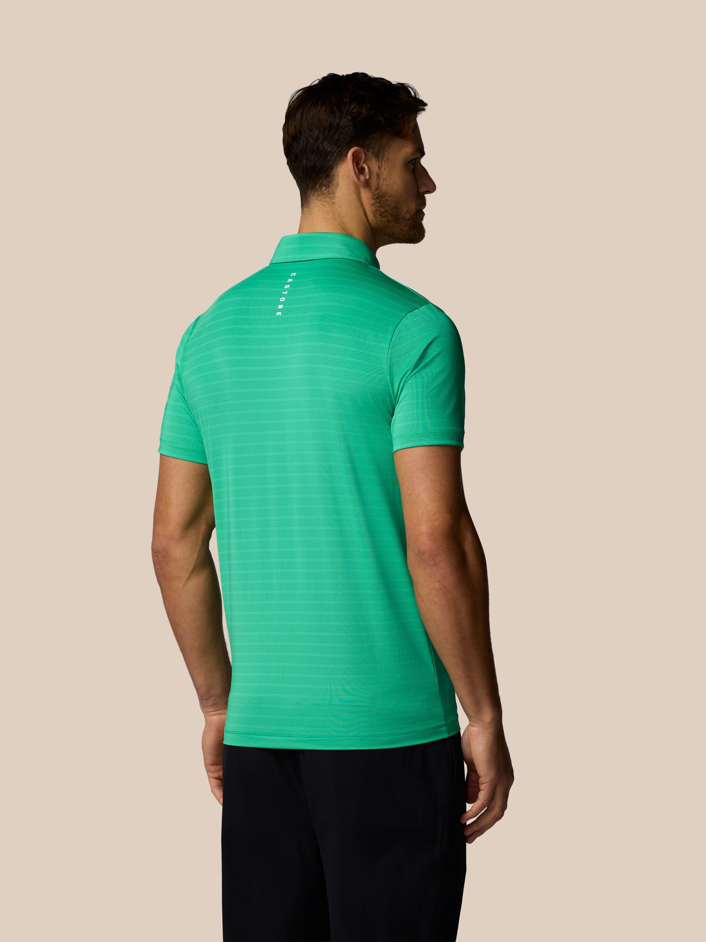 Man wearing a green polo shirt against a beige background