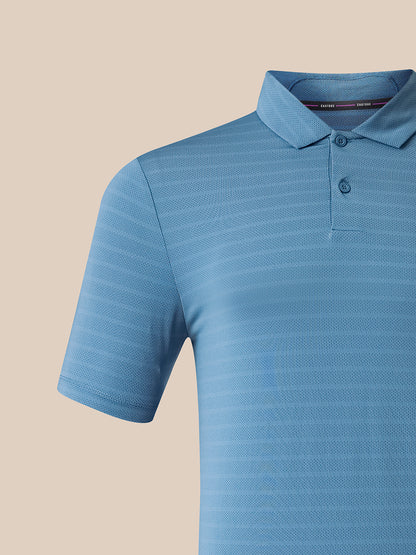 A close-up of a light blue short-sleeve polo shirt with a textured, fine-stripe pattern, set against a solid beige background.