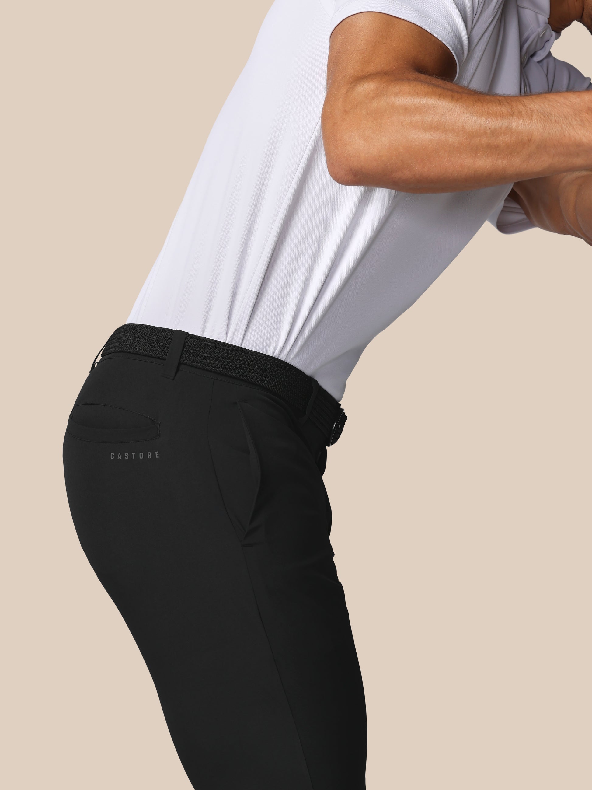Person wearing black pants with a visible brand logo on a beige background