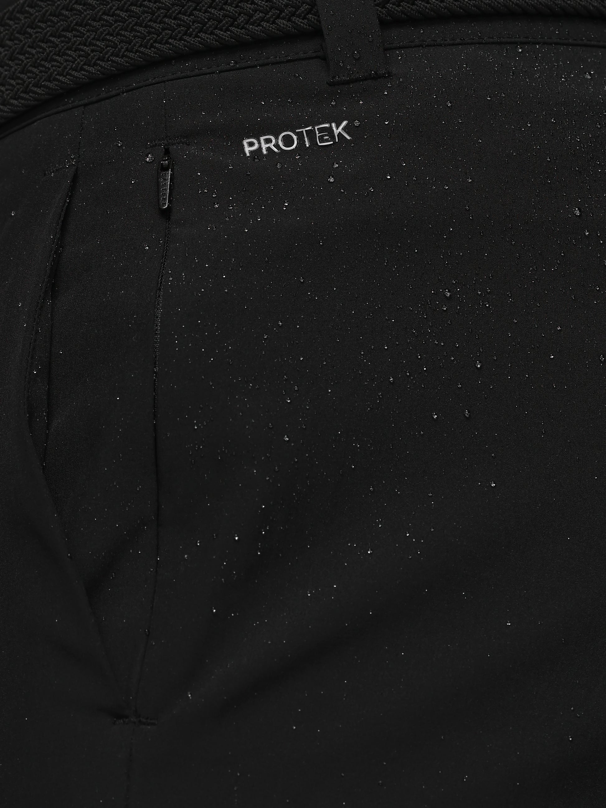 Close-up of a black jacket with 'PROTEK' branding on a textured background
