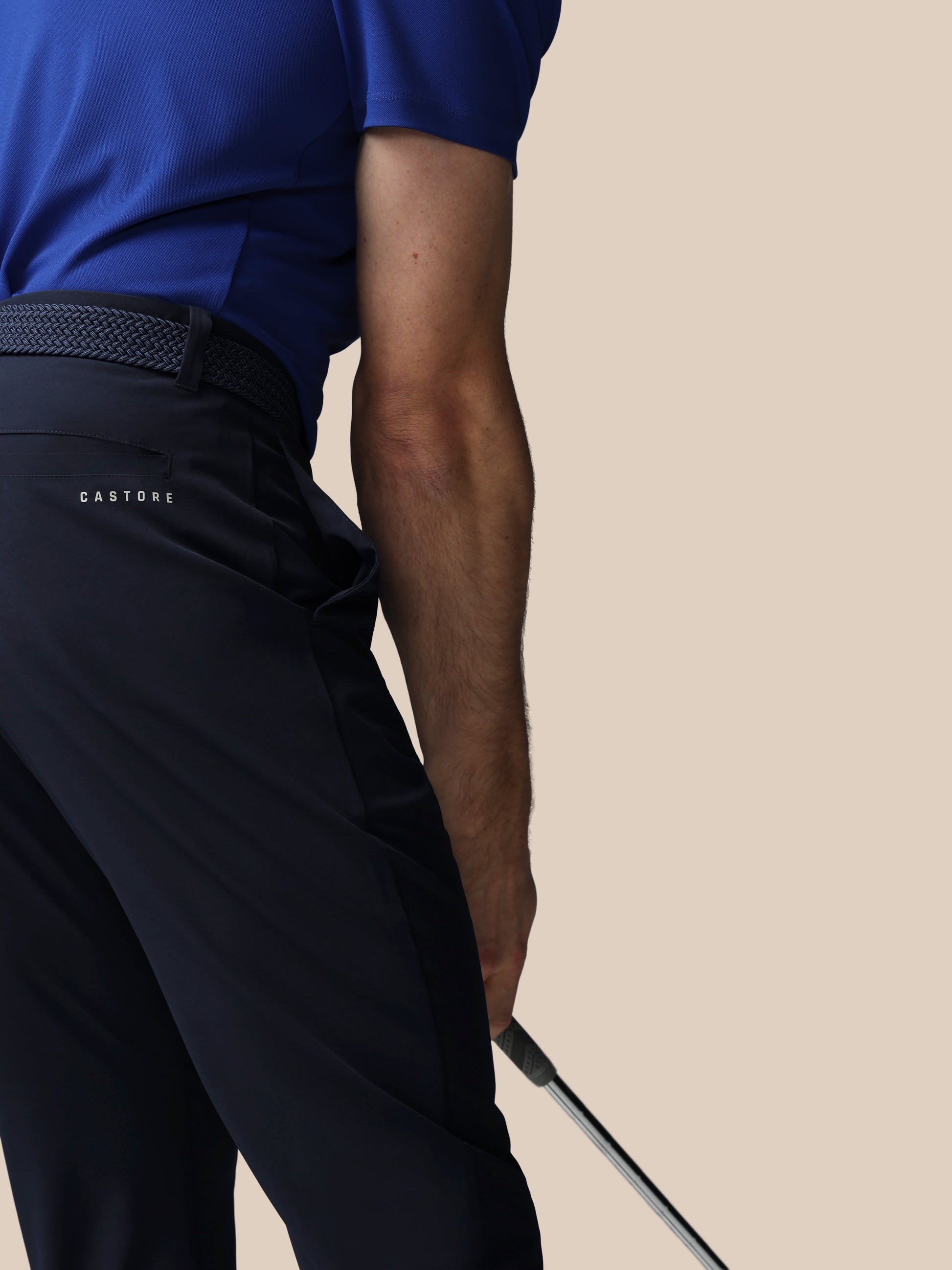 Person wearing navy pants with 'Castore' branding on a beige background