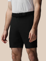 Person wearing black shorts and a white shirt on a beige background