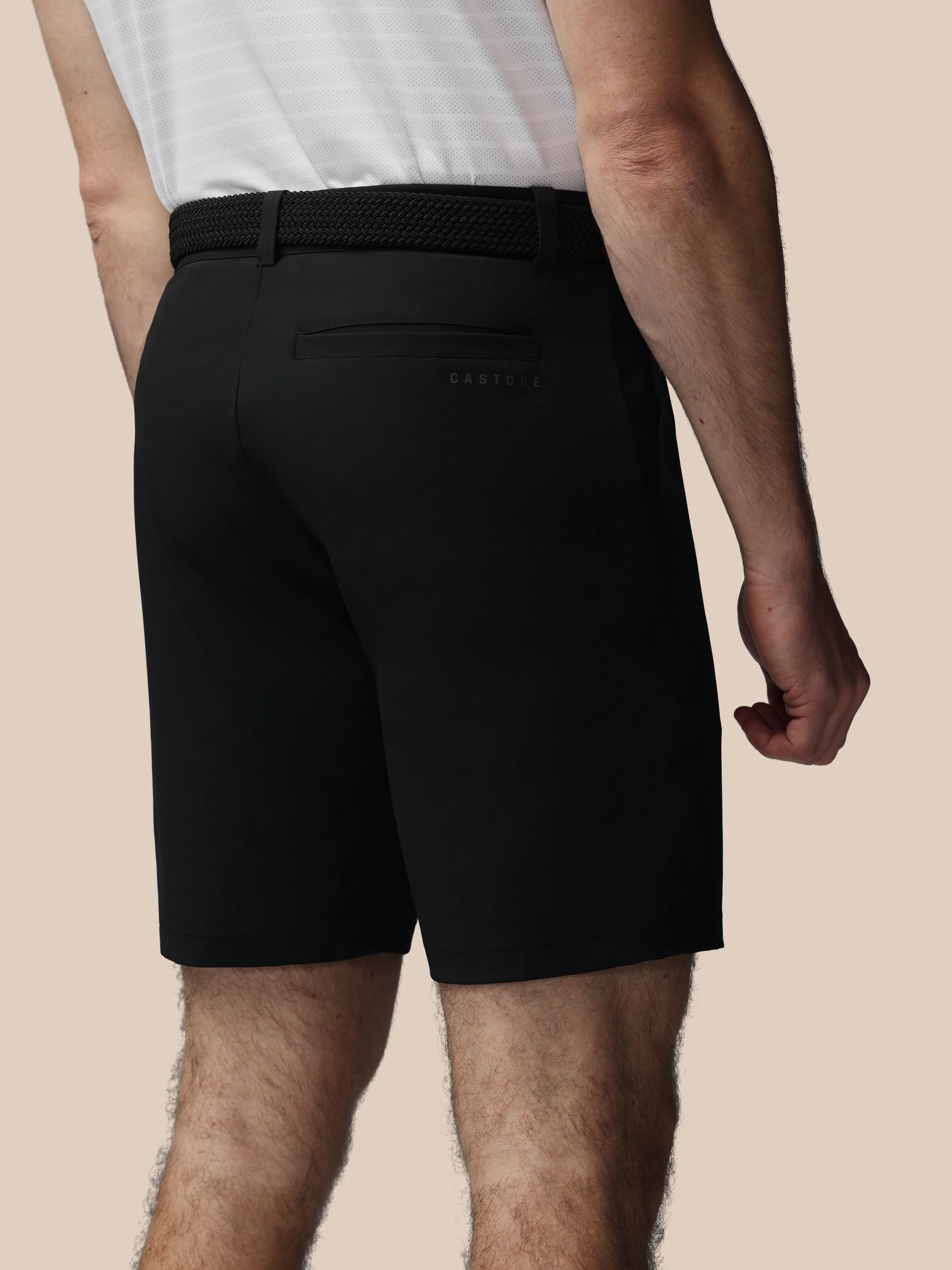 Person wearing black shorts with Castore logo on a beige background