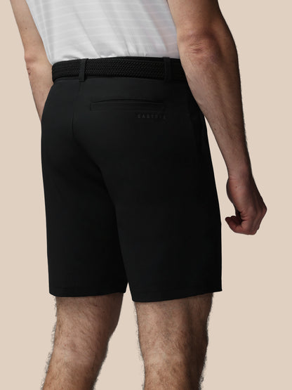 Person wearing black shorts with Castore logo on a beige background