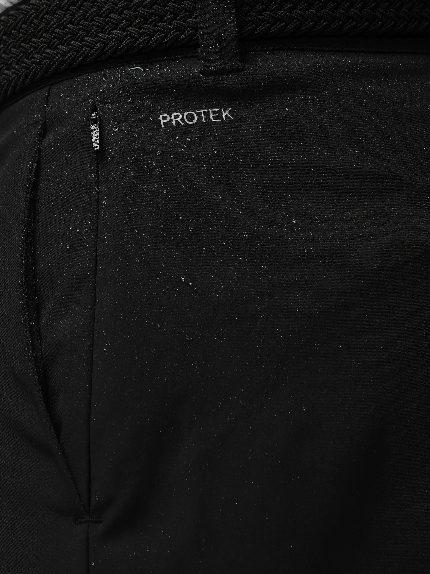 Close-up of a black jacket with 'PROTEK' branding on a dark background