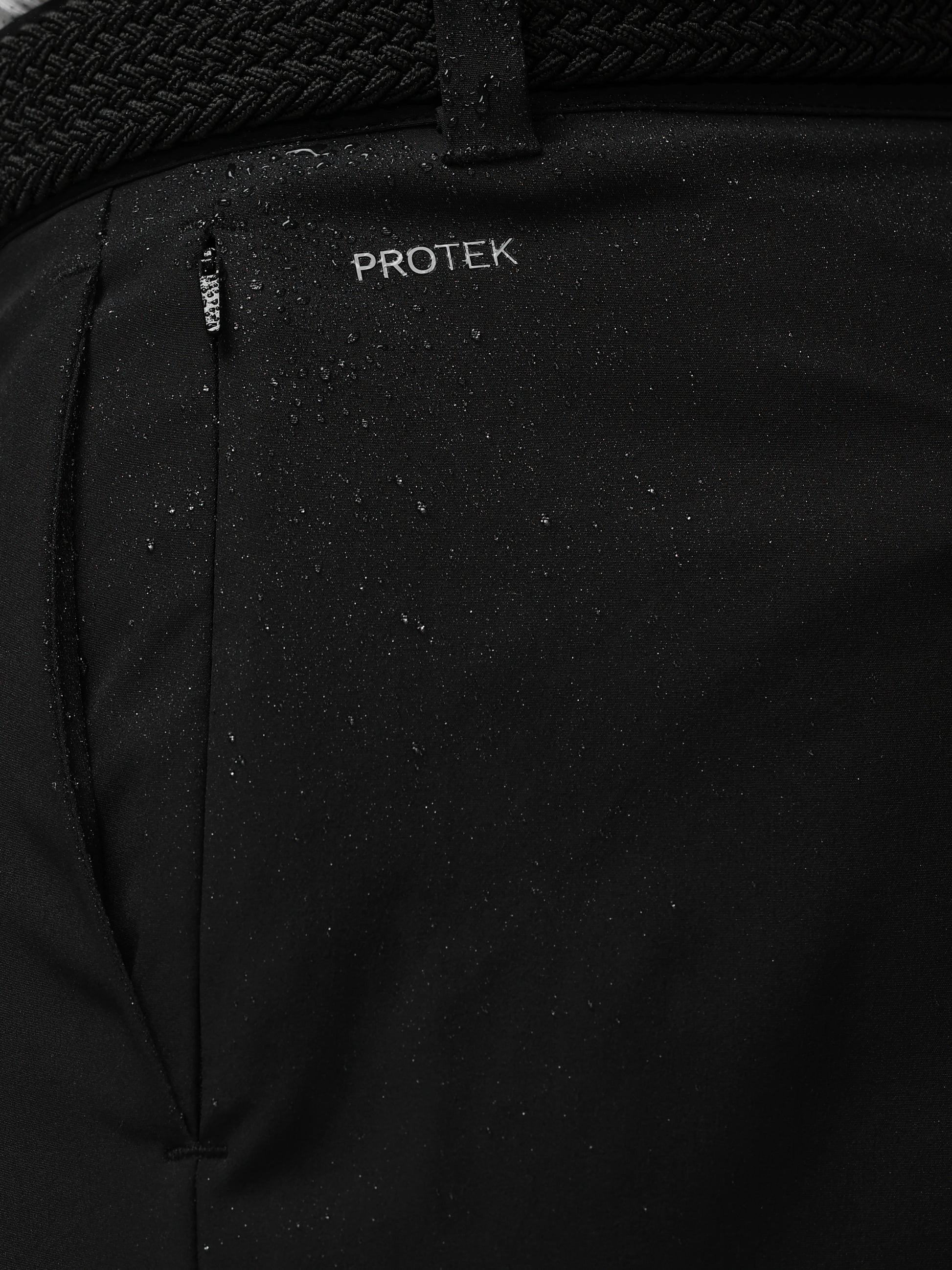 Close-up of a black jacket with 'PROTEK' branding on a dark background