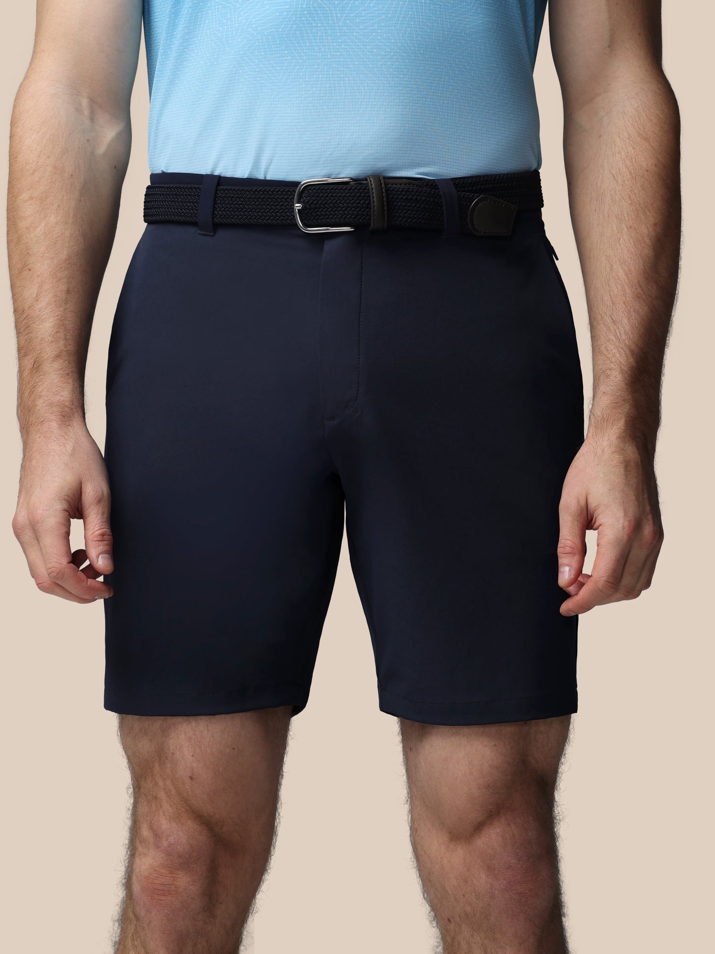 Person wearing navy shorts and a light blue shirt on a beige background