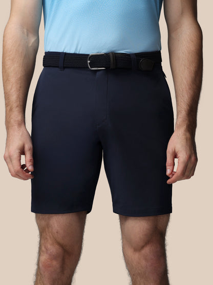 Person wearing navy shorts and a light blue shirt on a beige background