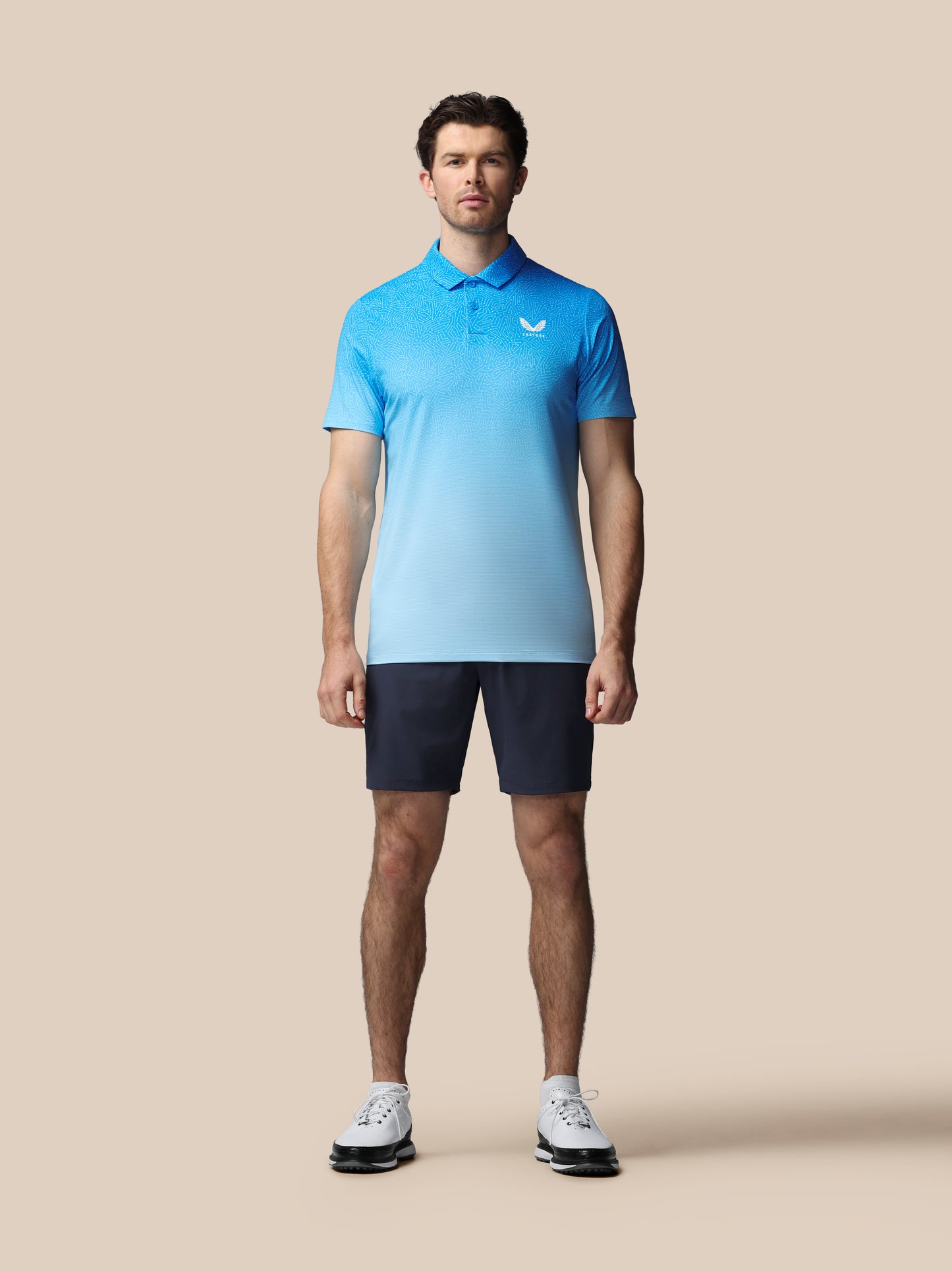 Man wearing a light blue polo shirt and black shorts on a beige background