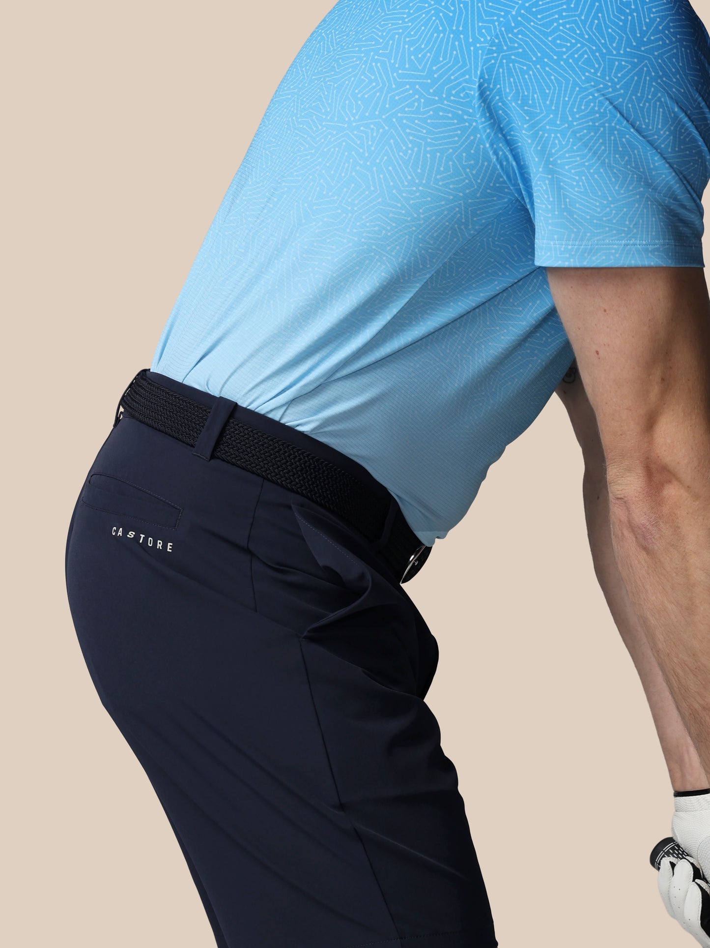 Person wearing navy pants with a black belt on a beige background