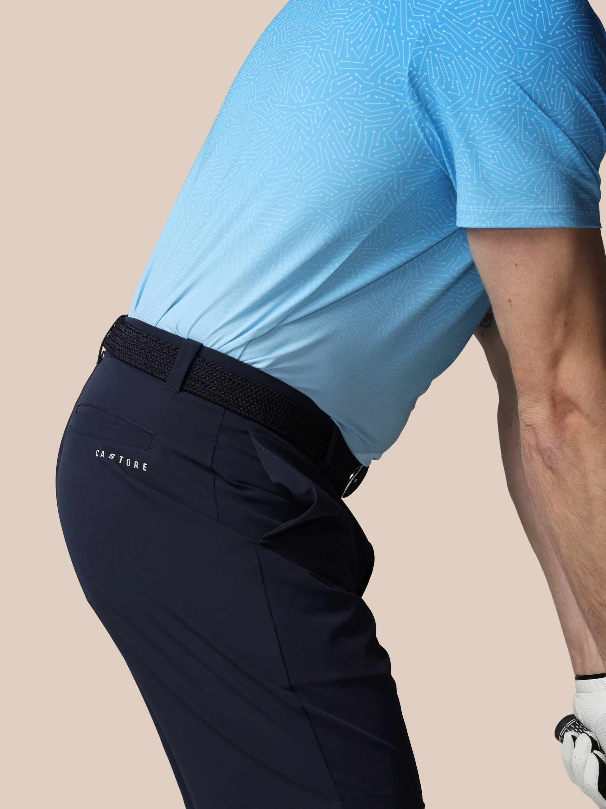 Person wearing navy pants with a black belt on a beige background