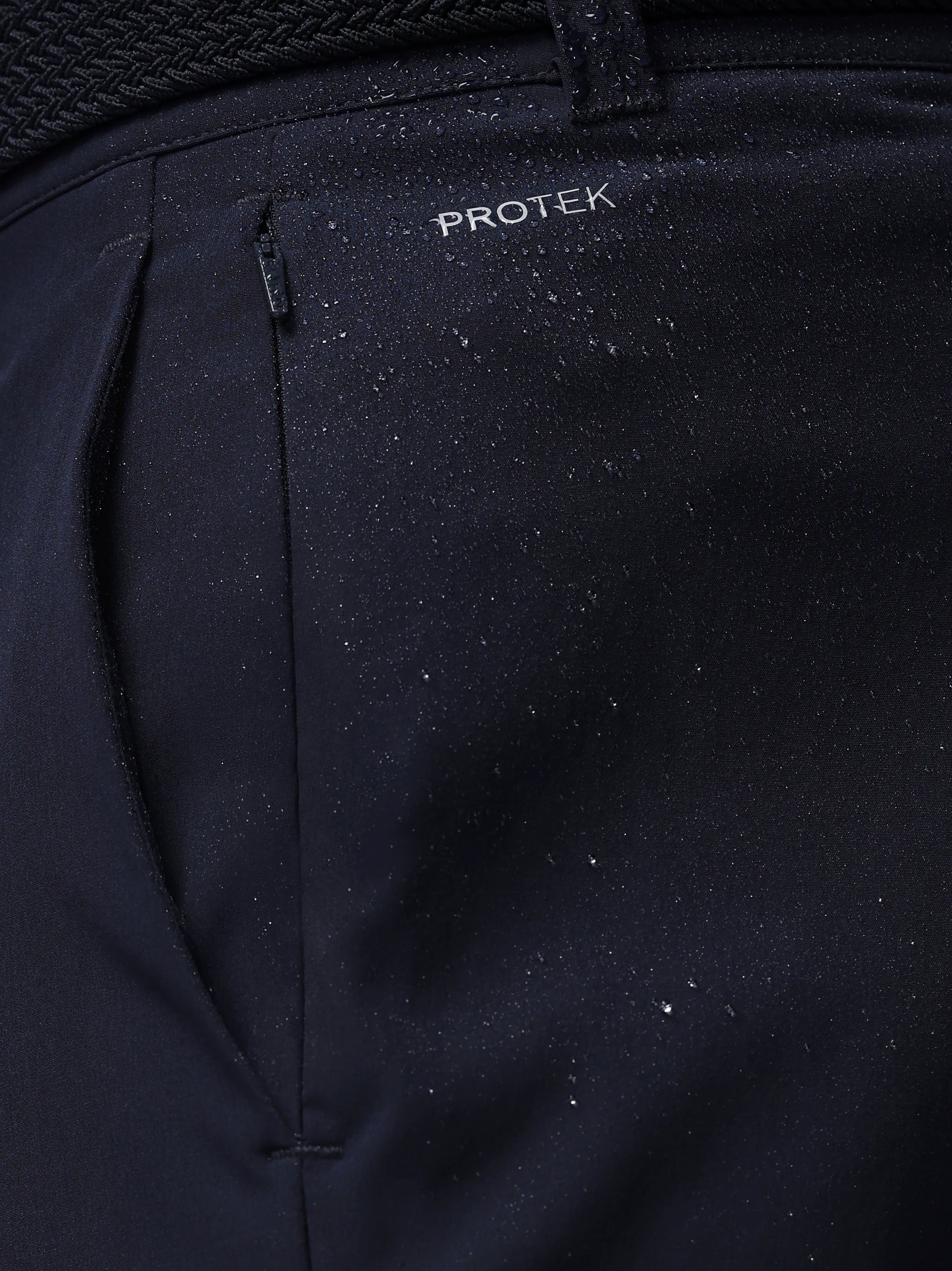 Close-up of navy pants with 'PROTEK' branding on a dark background