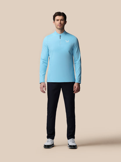 Man wearing a light blue long-sleeve shirt and black pants on a beige background