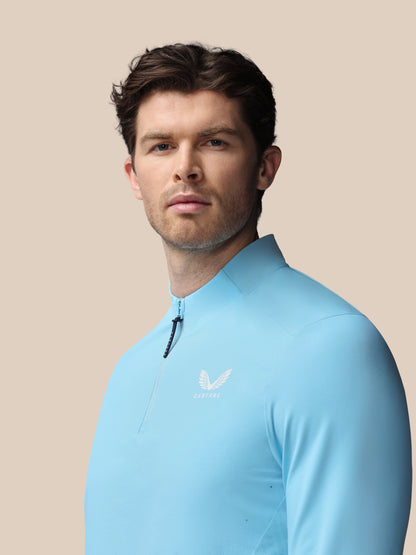 Man wearing a light blue long-sleeve shirt against a beige background