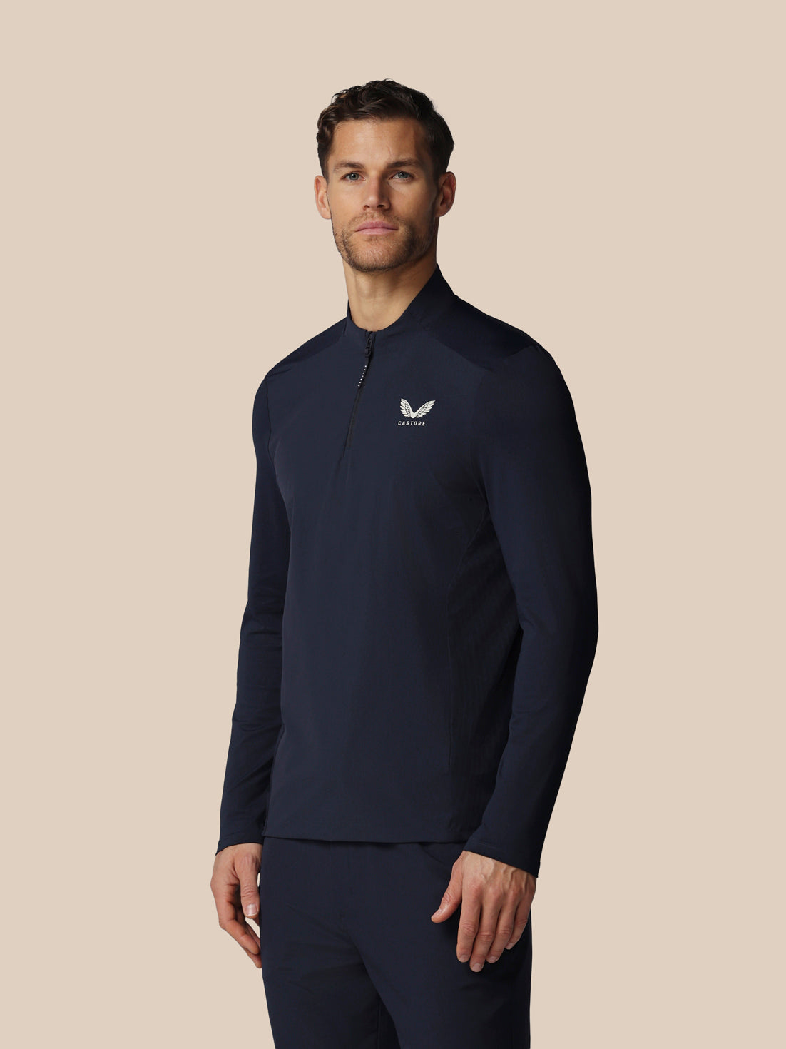 Man wearing a navy long-sleeve shirt with a logo on a beige background