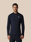 Man wearing a navy long-sleeve athletic shirt with Castore logo on a beige background