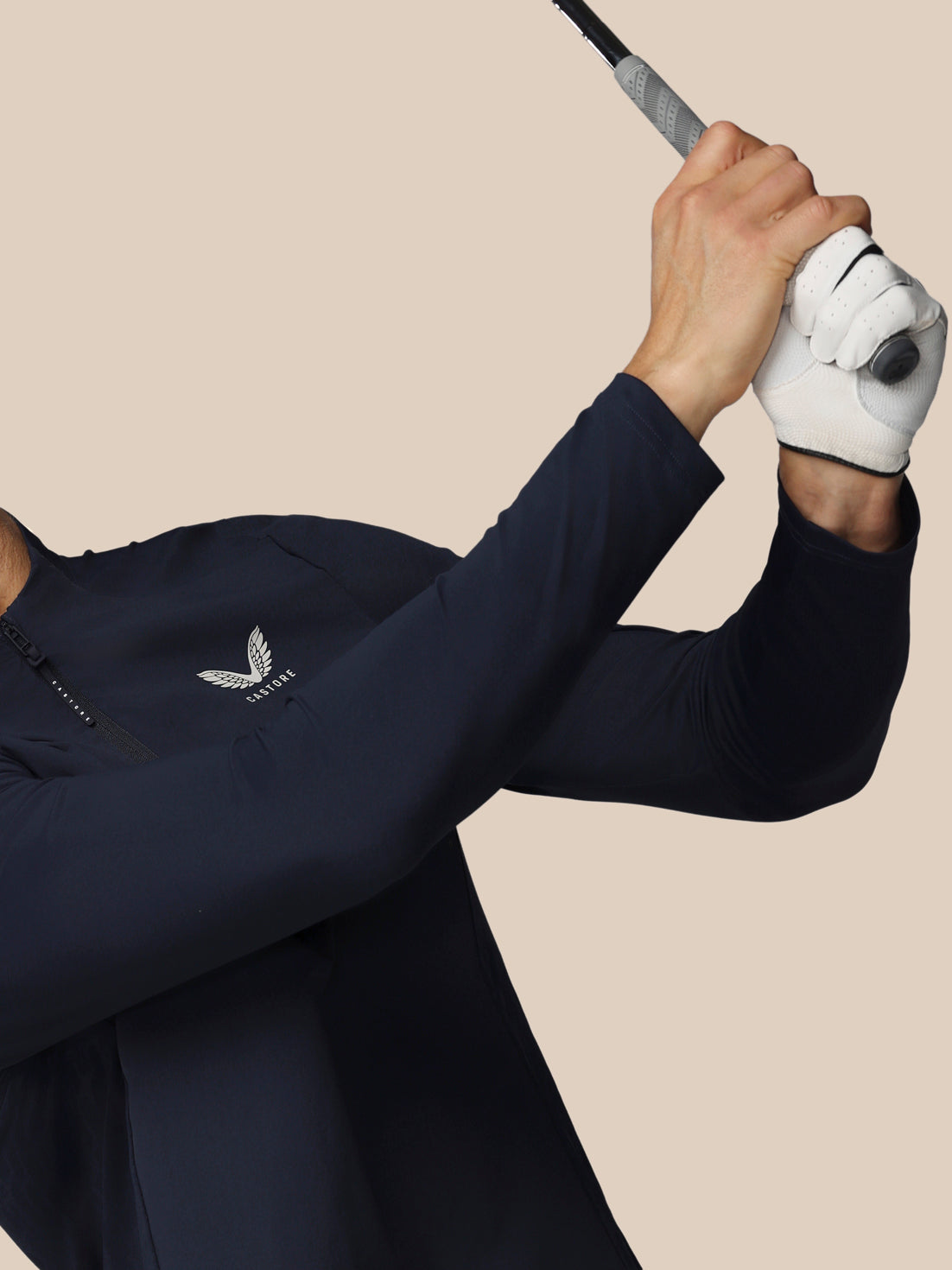 Person in navy blue golf outfit with white glove holding a golf club on a beige background