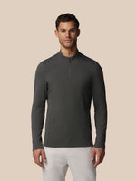 Man wearing a dark gray long-sleeve shirt with a quarter zip on a beige background