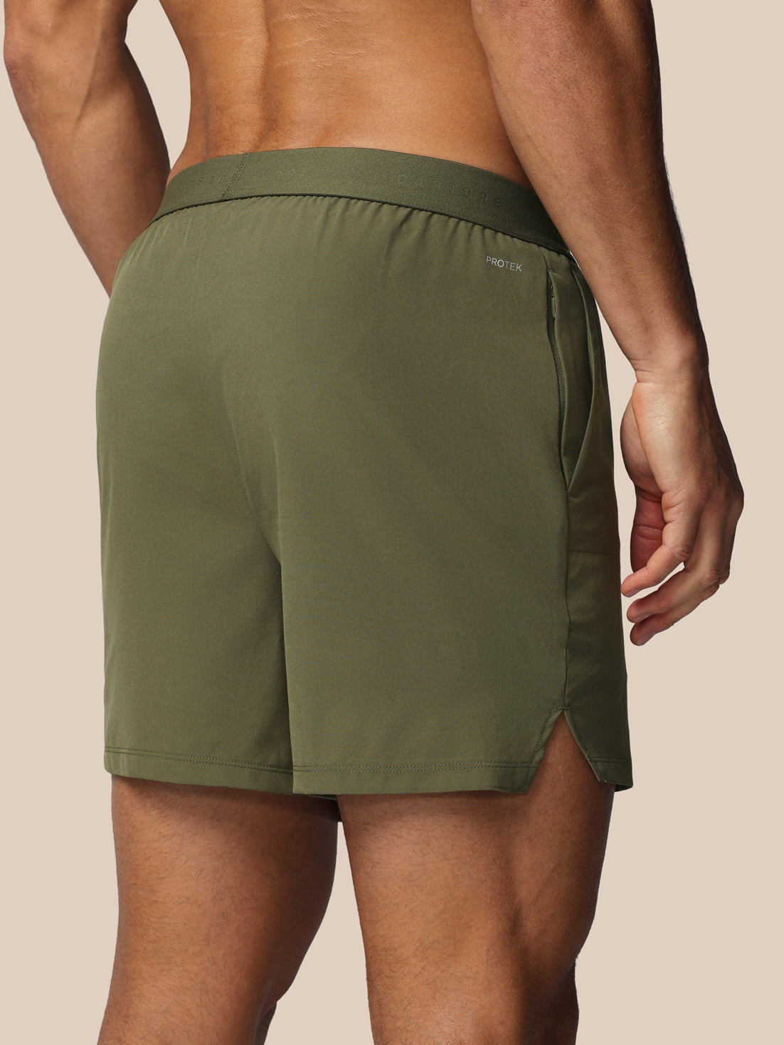 Person wearing green athletic shorts on a beige background