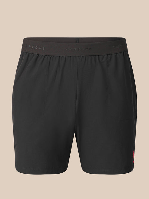 Black athletic shorts with an elastic waistband, shown against a solid beige background.