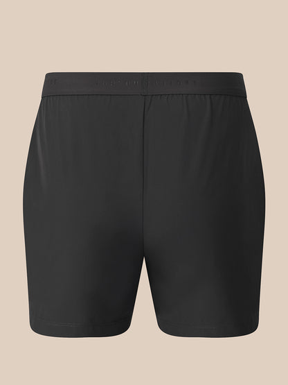 Black athletic shorts with a wide elastic waistband, shown flat against a solid beige background.