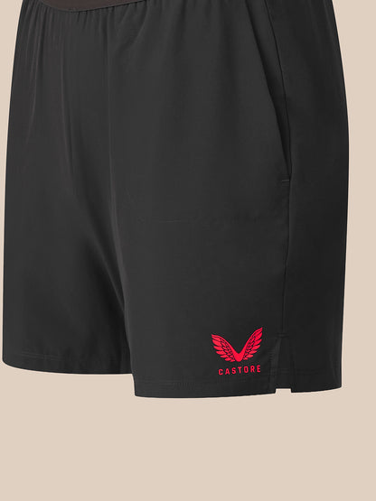 Black athletic shorts featuring a red winged logo and the brand name 'CASTORE' printed on the lower left leg, set against a solid beige background.