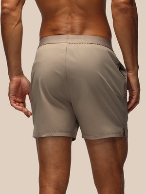 Back view of taupe Adapt Shorts with an elastic waistband and a Castore logo at the hem.
