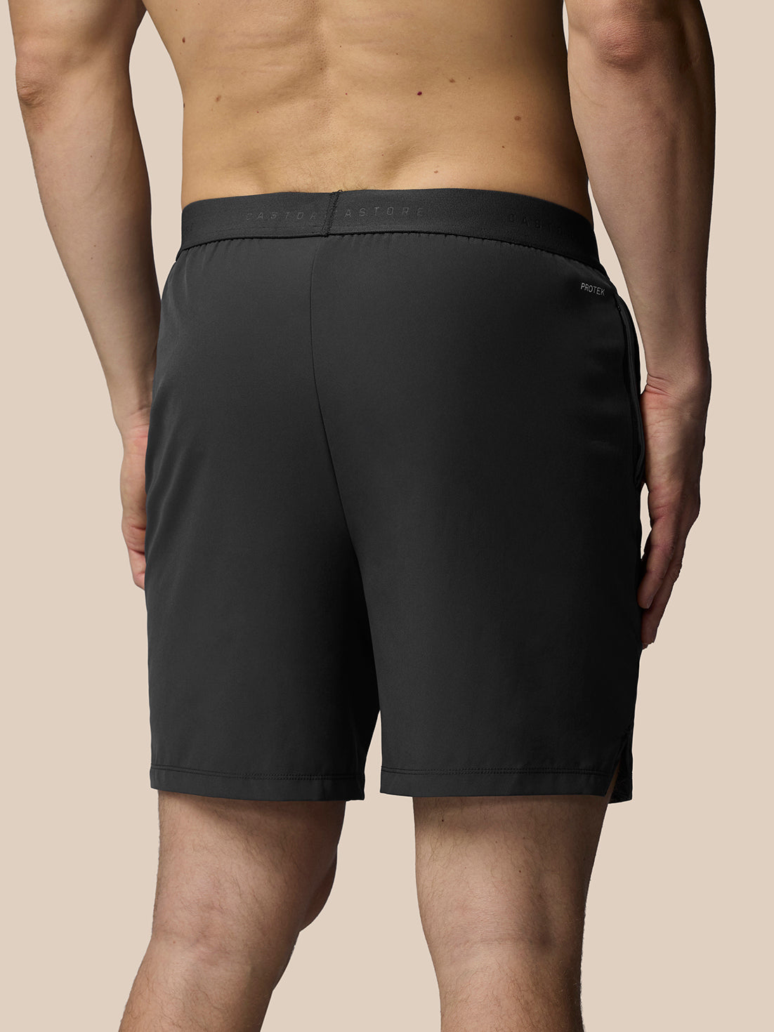 Person wearing black shorts on a beige background