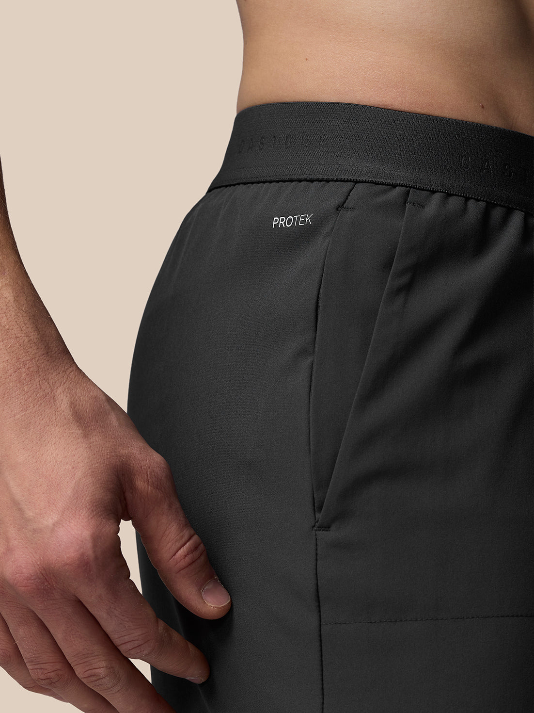 Black PROTEK pants with a beige background