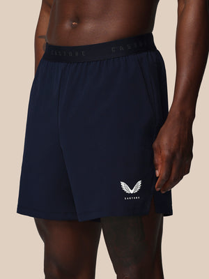 Navy athletic shorts with a logo on a beige background