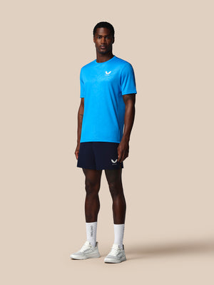 Man wearing a blue athletic shirt and black shorts on a beige background