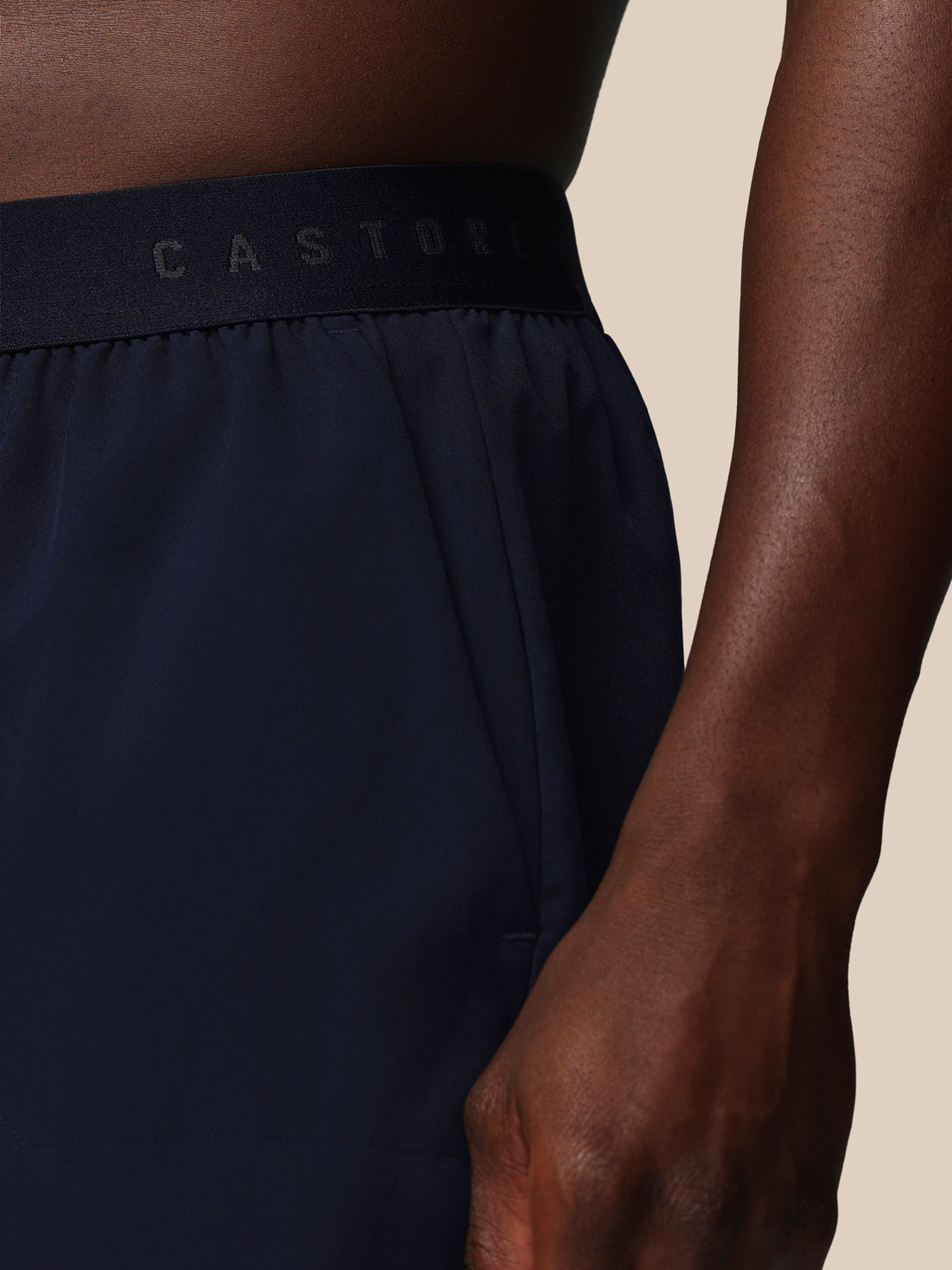 Navy athletic shorts with a visible brand logo on a beige background