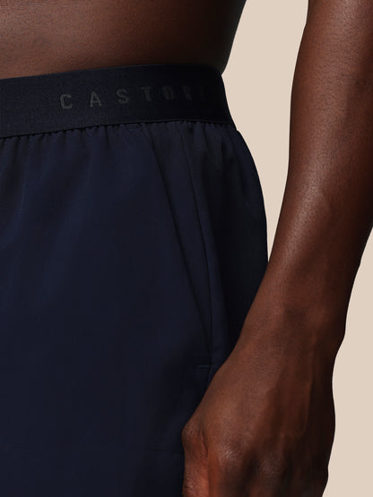 Navy athletic shorts with a visible brand logo on a beige background