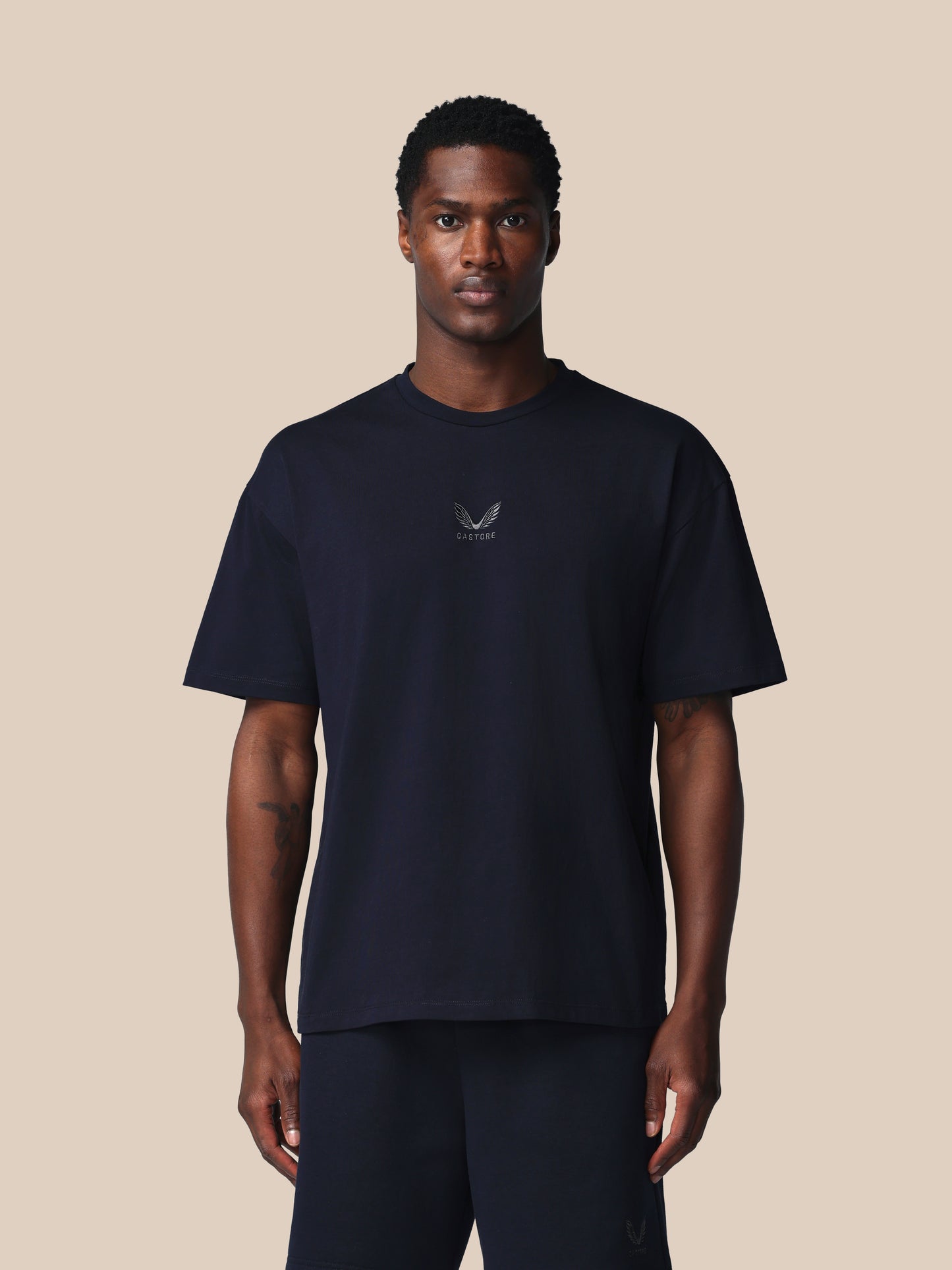 Man wearing a black t-shirt with a logo on a beige background