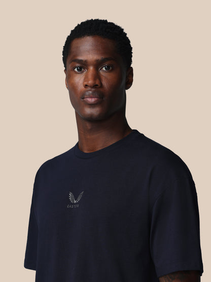 Man wearing a navy blue t-shirt with a logo on a beige background