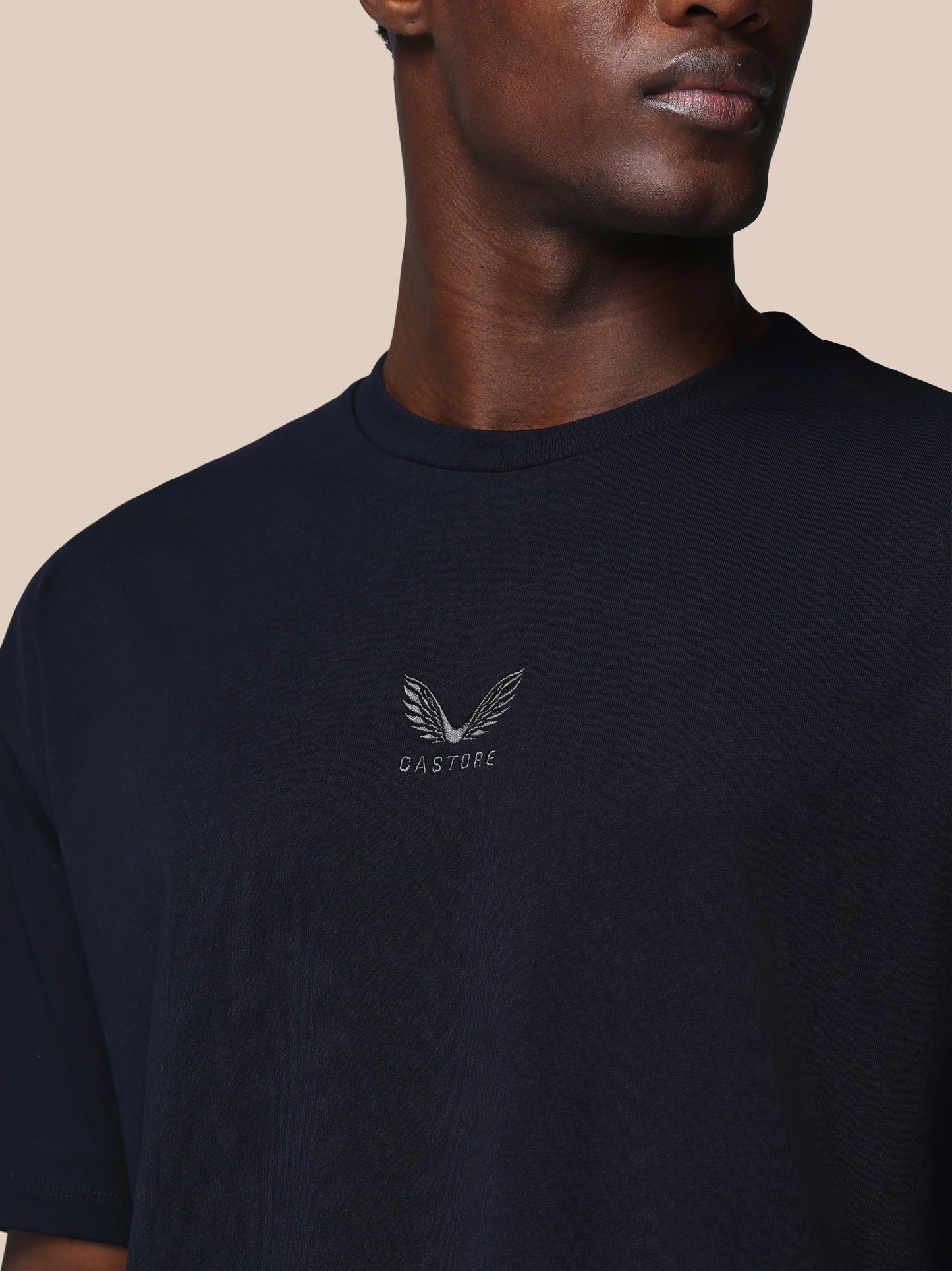 Man wearing a black t-shirt with a logo and text on a beige background