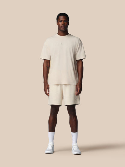 Man wearing a beige t-shirt and shorts set on a plain background