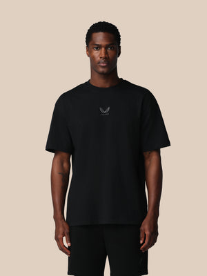 Man wearing a black t-shirt with a logo on a beige background