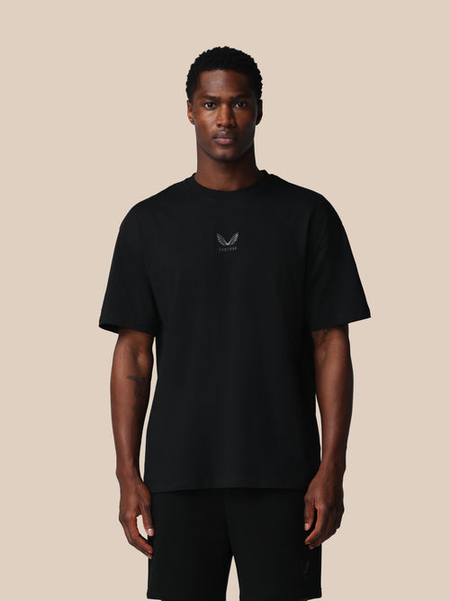 Man wearing a black t-shirt with a logo on a beige background