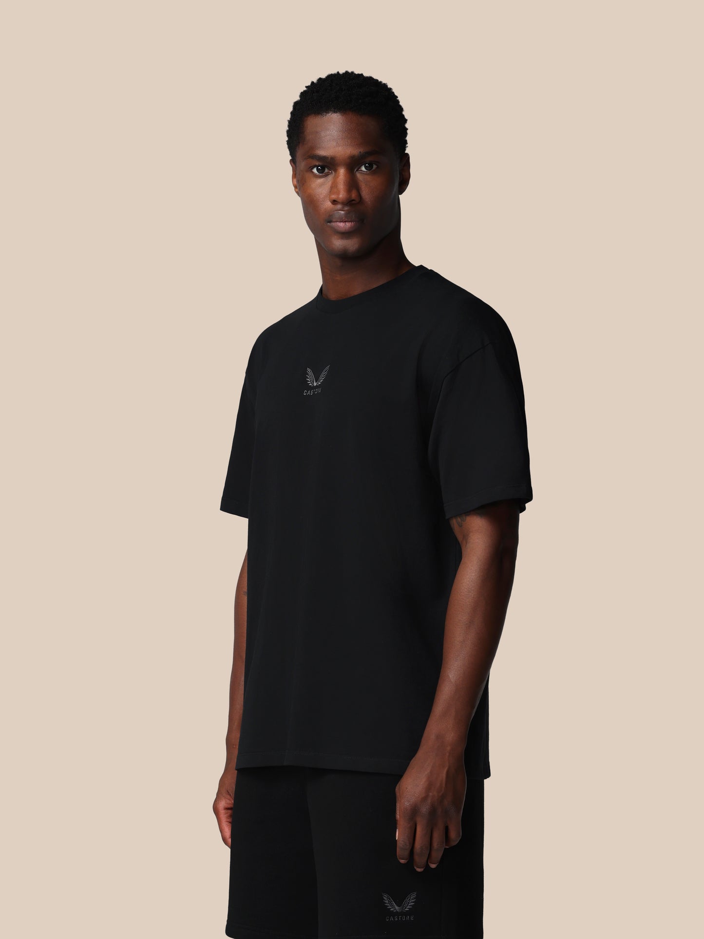 Man wearing a black t-shirt with a logo on a beige background