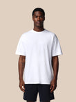 Man wearing a plain white t-shirt and black shorts on a beige background