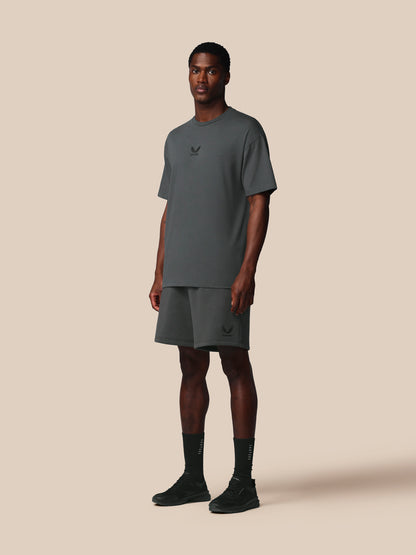 Man wearing a gray t-shirt and shorts set with a logo on a beige background