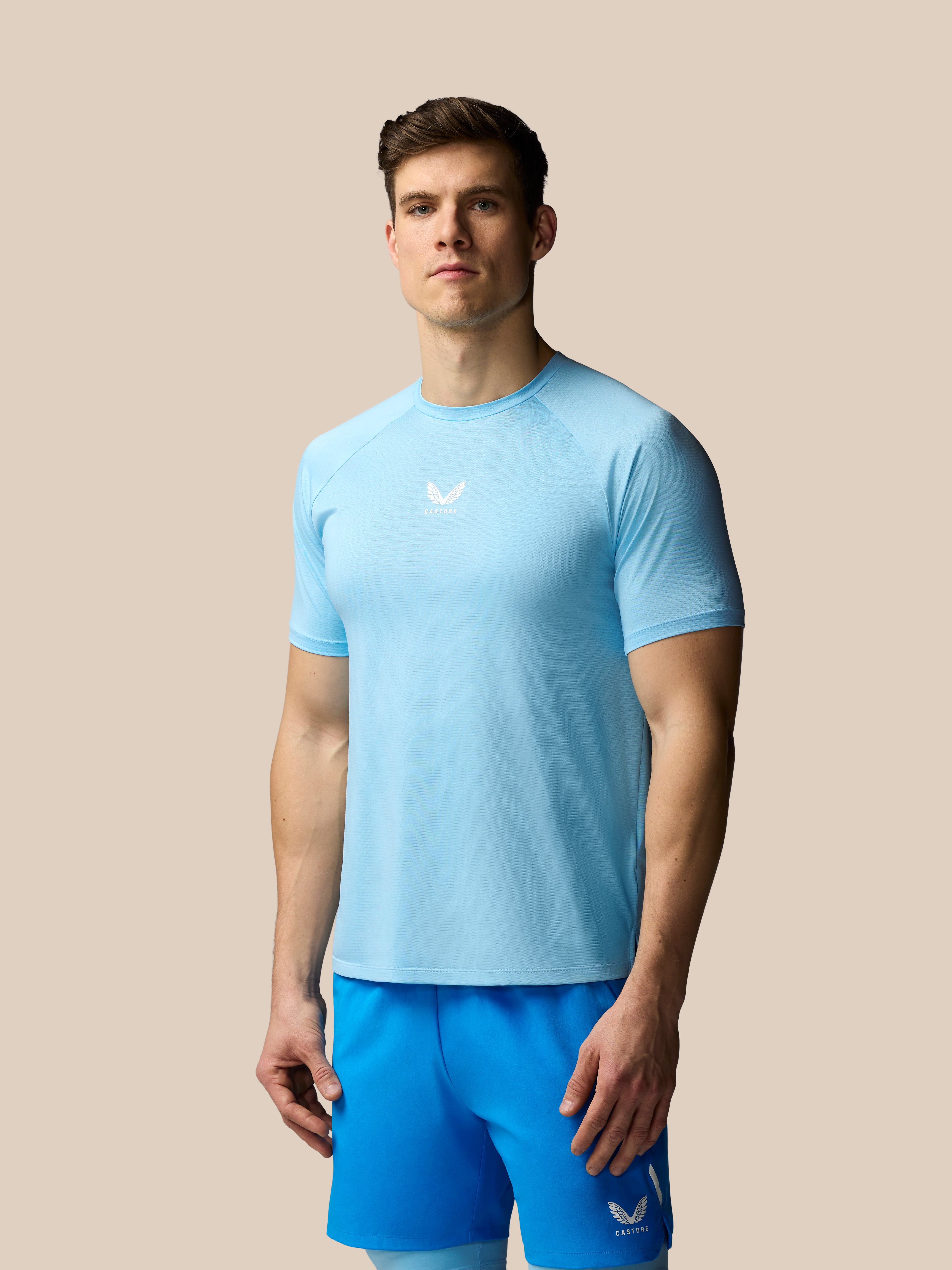 Man wearing a light blue athletic shirt and shorts on a beige background