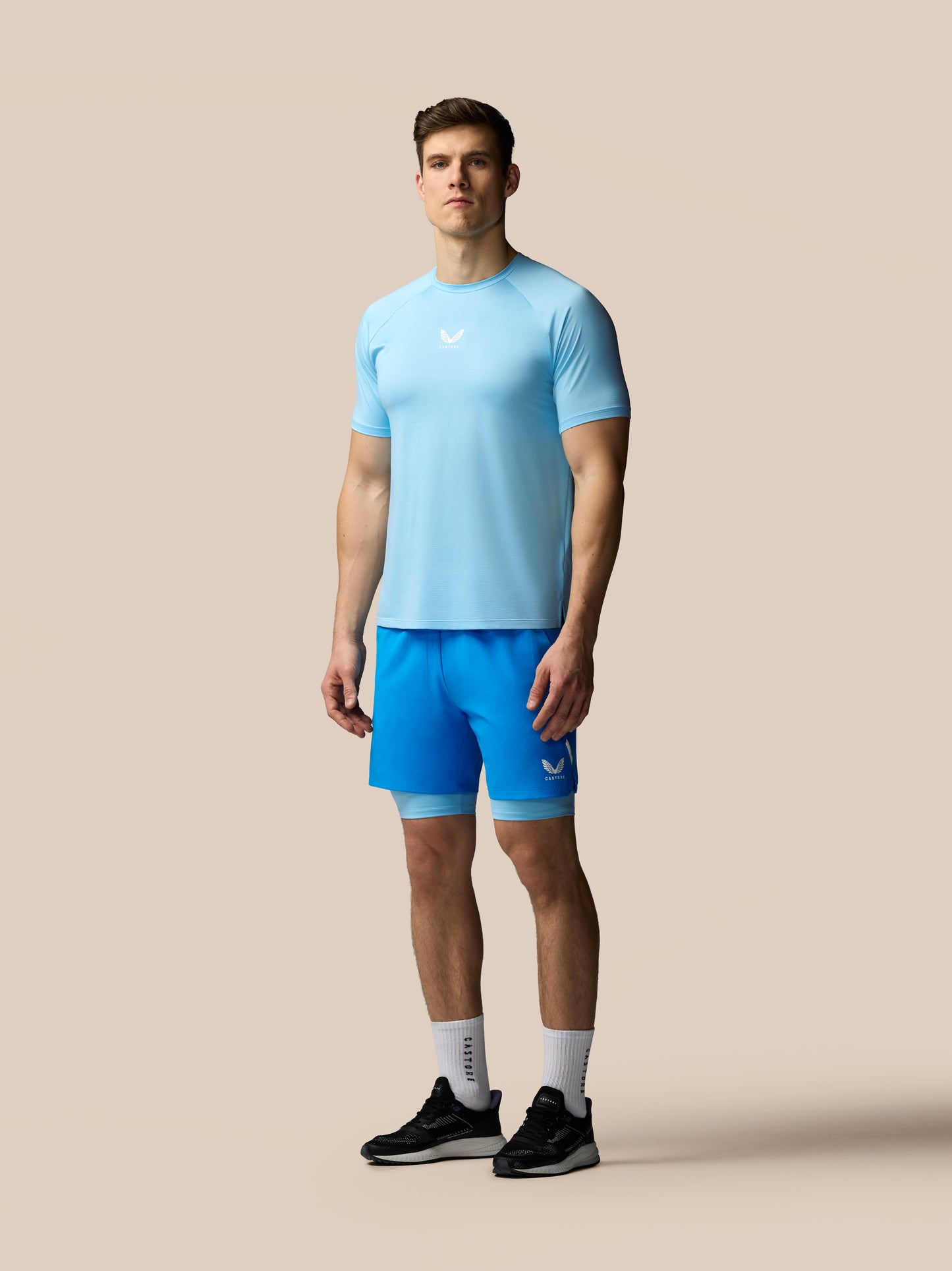 Man wearing a light blue athletic shirt and shorts on a beige background