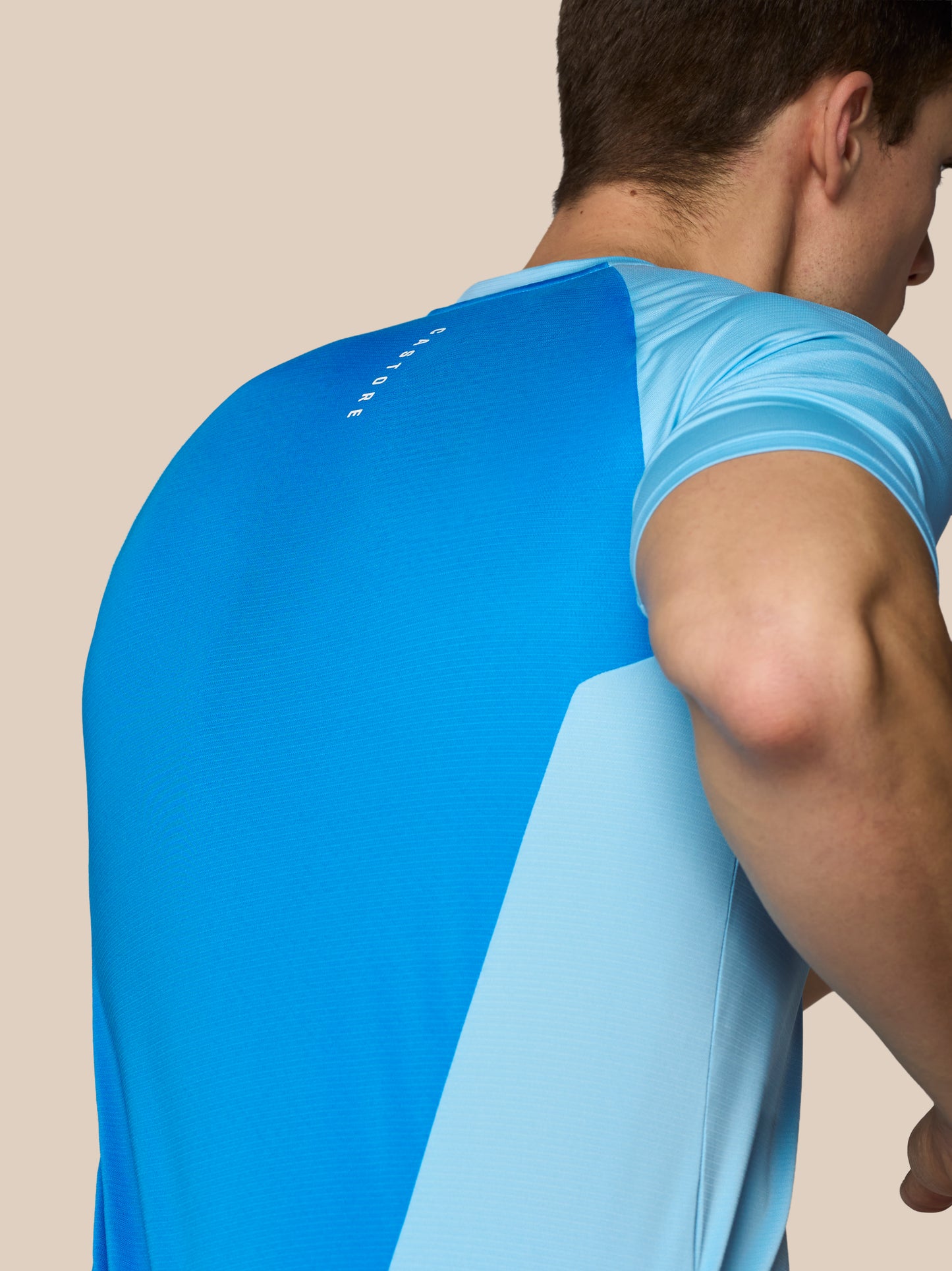 Man wearing a blue athletic shirt on a beige background
