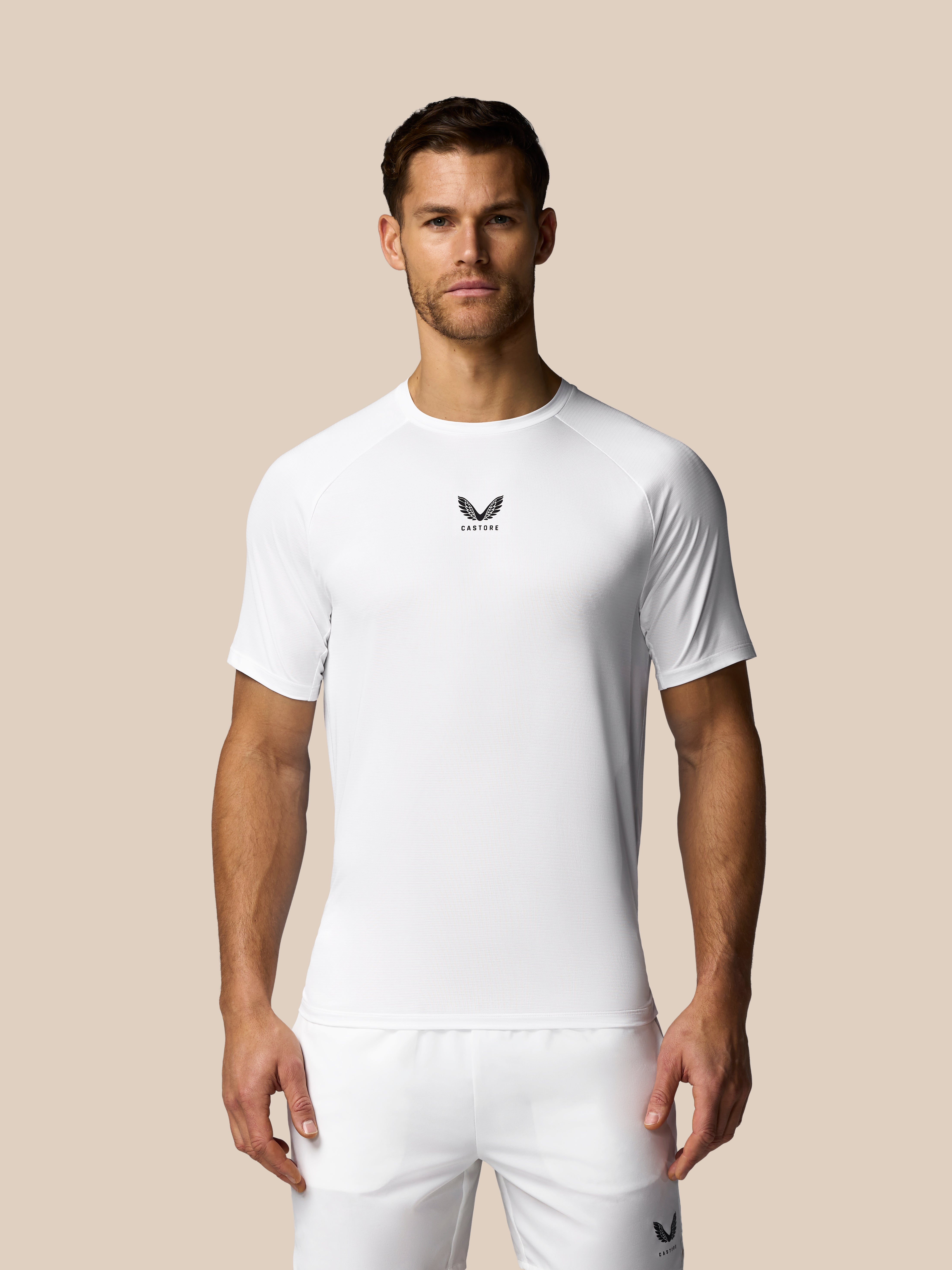 Man wearing a white t-shirt with a logo on a beige background