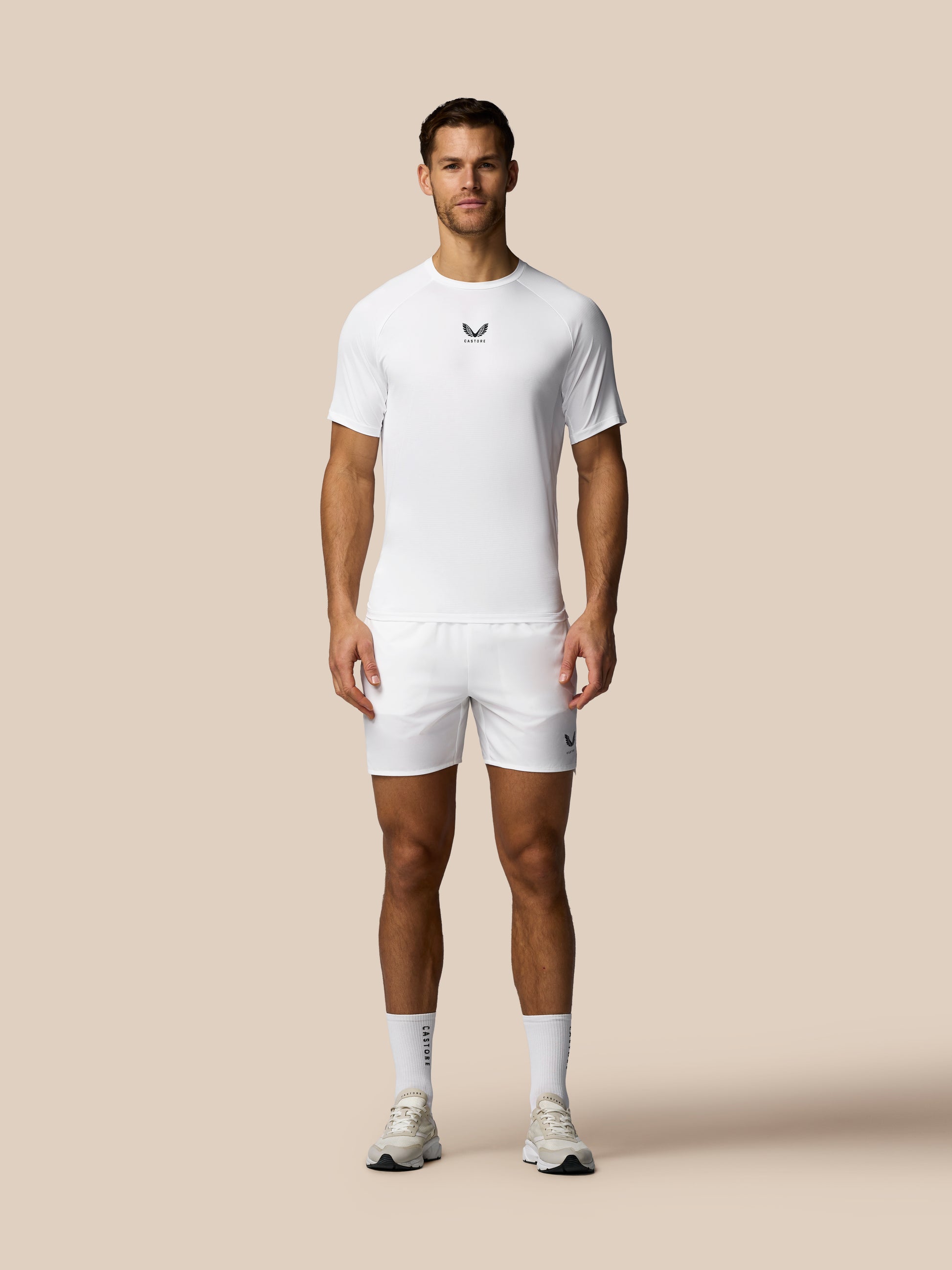 Man wearing a white t-shirt and shorts set on a beige background