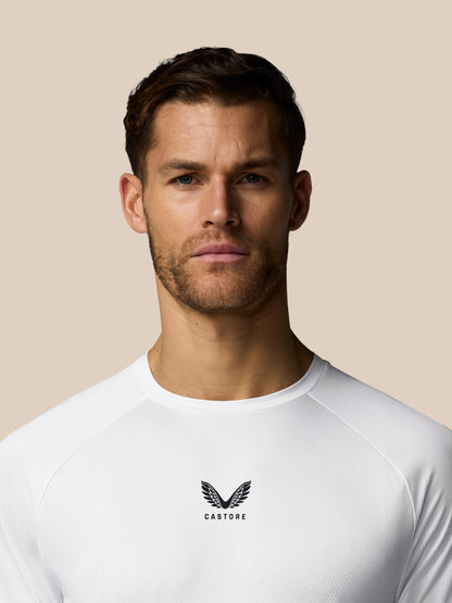 Man wearing a white athletic shirt with a logo on a beige background
