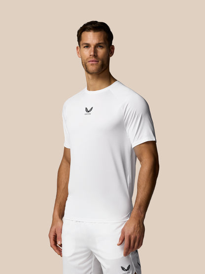 Man wearing a white athletic outfit with a logo on a beige background