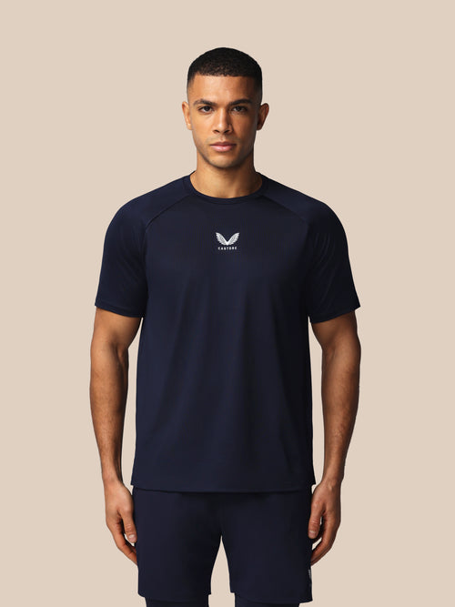 Man wearing a navy athletic outfit with a logo on a beige background